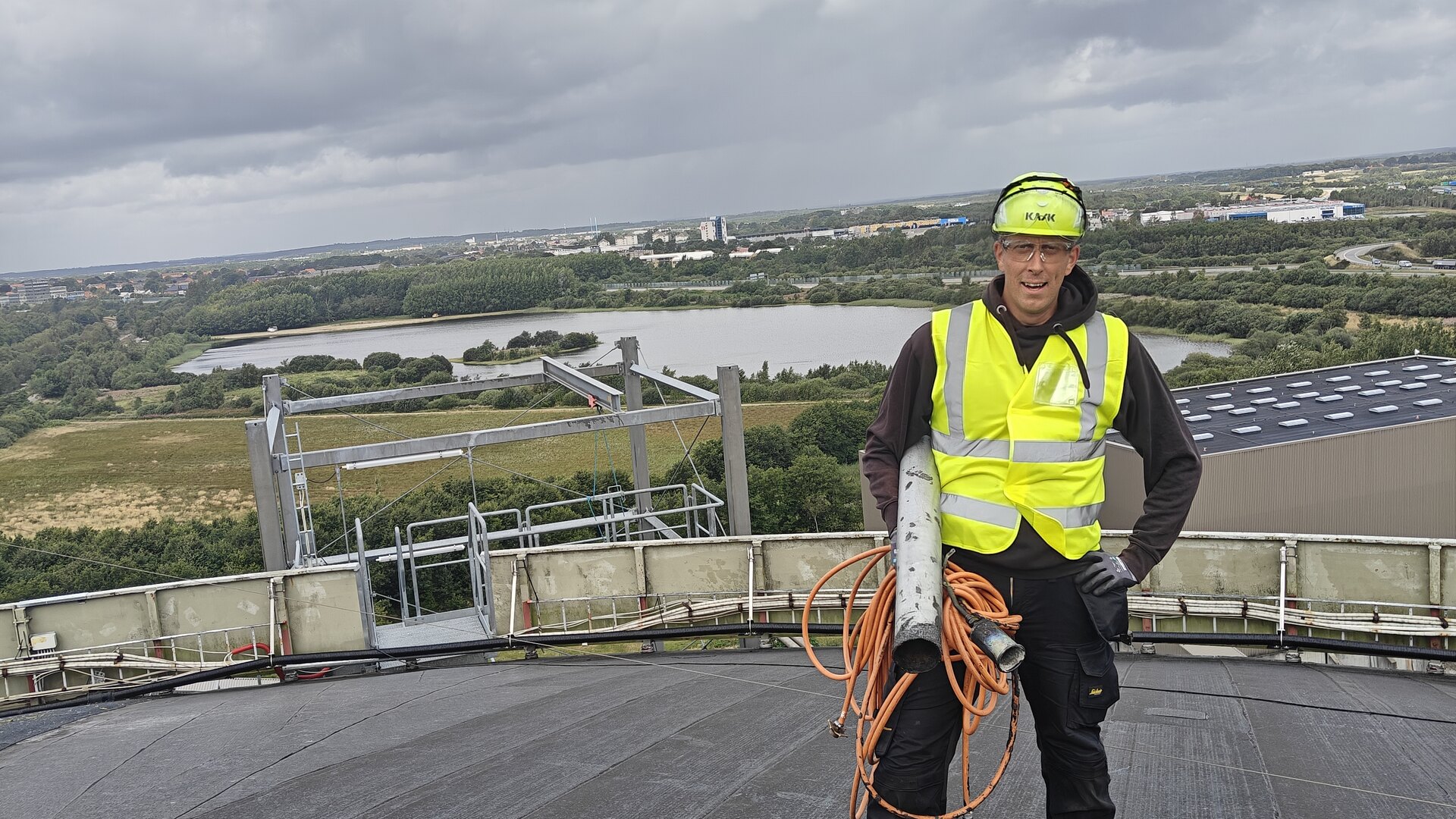 Mike Kielsgaard fra Haus360 på taget af en silo i Herning, med byen og søen bag sig