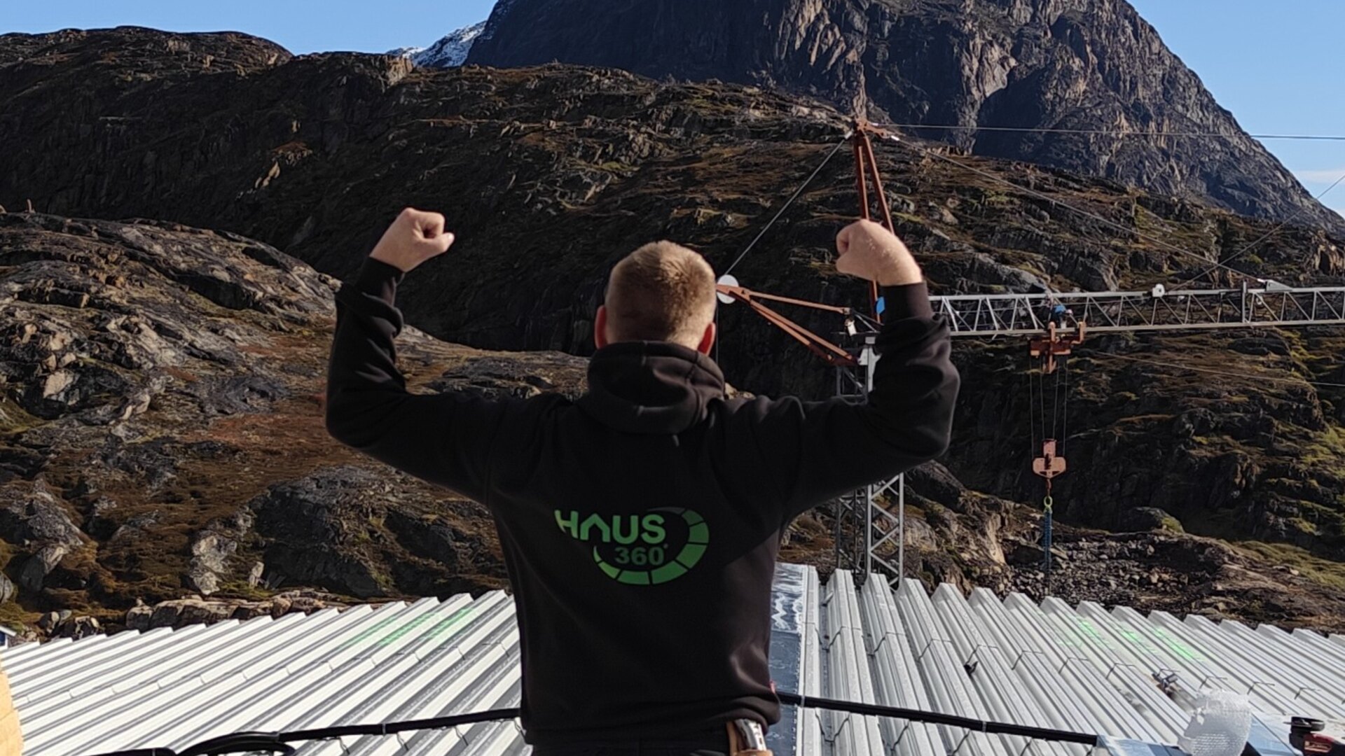 Tagdækker fra Haus360 på ståltaget af det nye forbrændingsanlæg i Sisimiut, med fjeldet bag sig